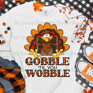 May include: White t-shirt with a Thanksgiving turkey graphic and the text "Gobble 'Til You Wobble" in orange and black plaid.