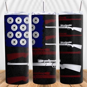 Puede incluir: Un vaso de acero inoxidable con un diseño de bandera estadounidense en negro y azul. La bandera presenta un patrón de cartuchos de escopeta de calibre 12 y siluetas de rifles con miras telescópicas.