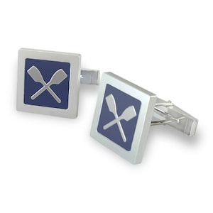 May include: A pair of silver cufflinks with a blue enamel background and a silver design of two crossed oars.