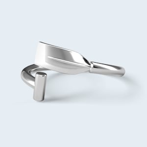May include: A silver ring shaped like an oar, a traditional rowing tool.