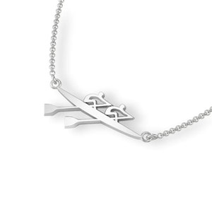 May include: Silver necklace with a pendant featuring a silhouette of two rowers in a rowing boat with oars.