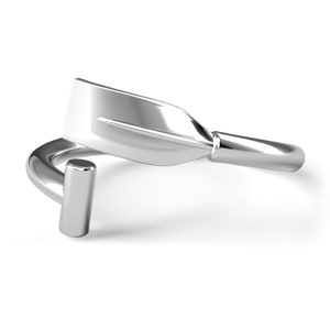 May include: Silver ring with a stylized oar design. The ring is open and adjustable.