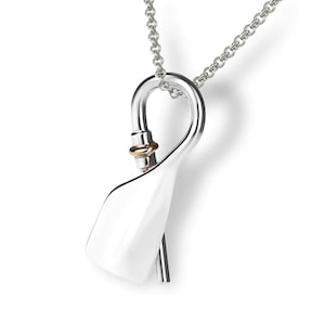 May include: A silver pendant necklace with a unique, abstract design. The pendant features a smooth, curved shape with a small gold accent. The chain is silver and has a delicate, linked design.