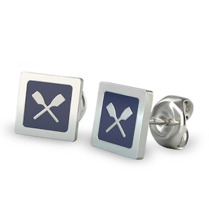 May include: Silver-tone square stud earrings. Each earring features a navy blue square with a white crossed oars design. The earrings have a post and butterfly backing.