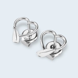 Op de afbeelding: Een paar zilveren hartvormige oorbellen met een klein peddeldetail op elke oorbel.