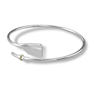 Peut inclure: Un bracelet jonc en argent avec un pendentif en forme de rame en argent et une petite bague dorée.