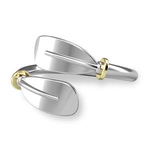 May include: A silver ring with two intertwined paddle-shaped elements. The ring features two gold accents on the sides.
