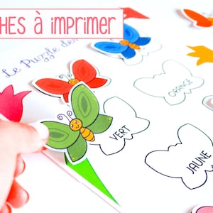 May include: A printable puzzle game for kids featuring colorful butterflies and the French words "Le Puzzle des Couleurs". The game includes a set of butterfly cutouts in different colors, including red, blue, green, orange, purple, yellow, and pink. The butterflies are placed on a sheet of paper with outlines of butterflies in the same colors, labeled with the French words for each color.