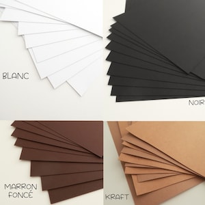 May include: Four stacks of cardstock paper in different colors: white, black, brown, and kraft. The stacks are labeled "BLANC", "NOIR", "MARRON FONCE", and "KRAFT".