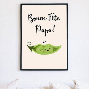 May include: A framed print with a light beige background. The print features black text that reads 'Bonne Fete Papa!' and a green pea pod with two smiling peas inside.