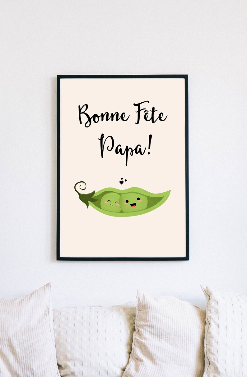 May include: A framed print with a light beige background. The print features black text that reads 'Bonne Fete Papa!' and a green pea pod with two smiling peas inside.