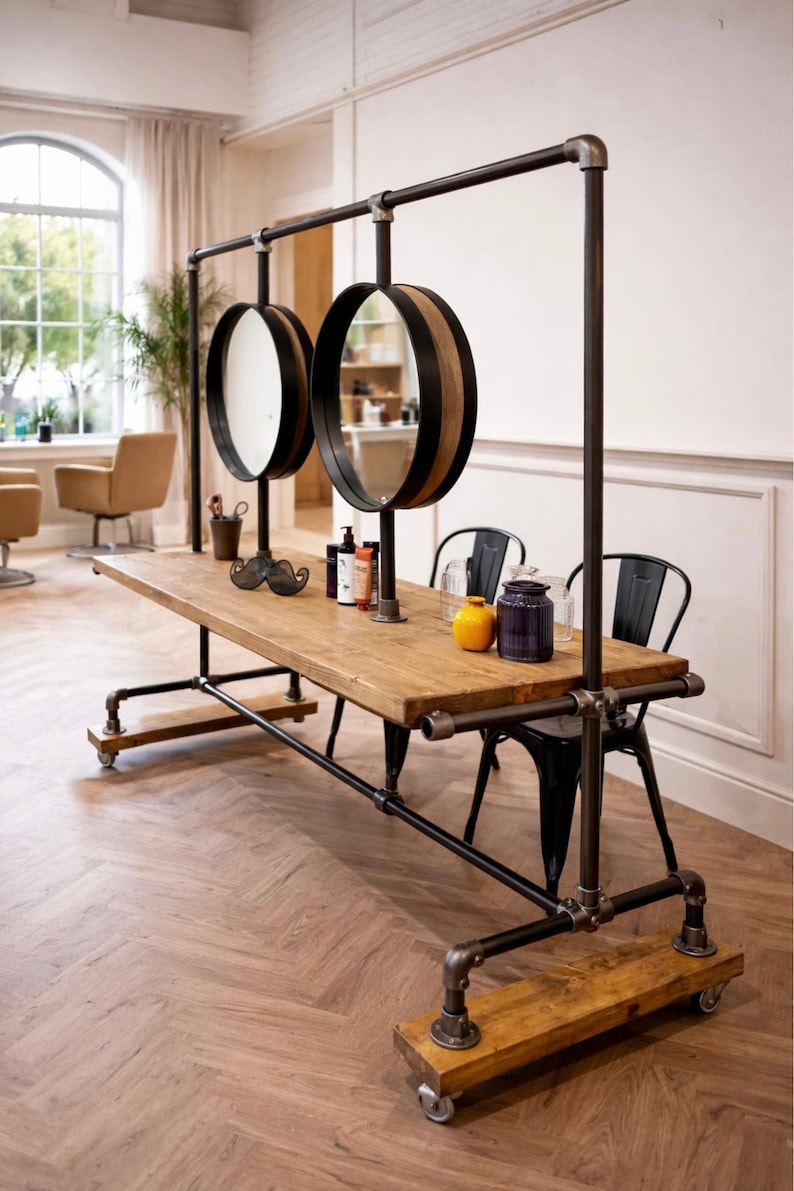 K&ouml;nnte beinhalten: Ein rustikaler Salon-Arbeitsplatz mit einer Holzplatte und einem schwarzen Metallrahmen. Zwei kreisf&ouml;rmige Spiegel mit Holz- und schwarzem Besatz h&auml;ngen &uuml;ber dem Tisch. Der Arbeitsplatz umfasst einen Schnurrbart-Dekoration, Flaschen und Gl&auml;ser. Der Arbeitsplatz ist auf R&auml;dern.