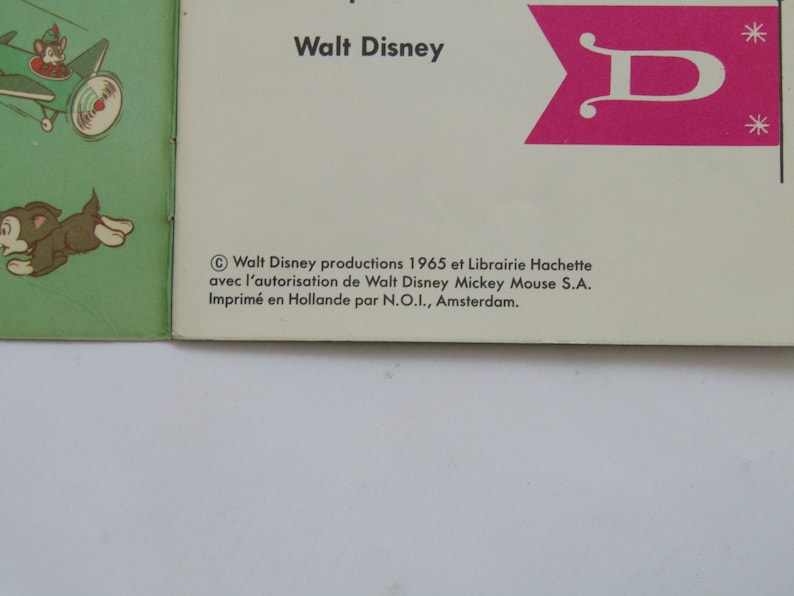 May include: Vintage Walt Disney book cover featuring a green airplane with a mouse pilot and a brown puppy. The cover includes the text "Walt Disney" and a pink flag with a white "D". Copyright information is also visible.