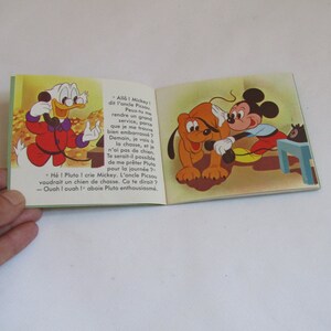 May include: A vintage children's book featuring Mickey Mouse and Pluto. Mickey is on the phone with Donald Duck, who is asking for Pluto to go hunting with him. The book is illustrated in a cartoon style with bright colors.