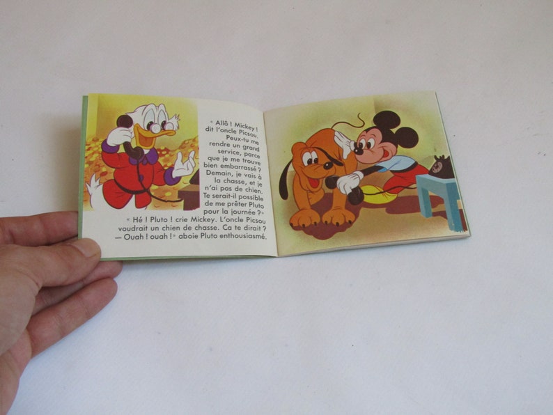 May include: A vintage children's book featuring Mickey Mouse and Pluto. Mickey is on the phone with Donald Duck, who is asking for Pluto to go hunting with him. The book is illustrated in a cartoon style with bright colors.