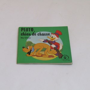 May include: A vintage children's book cover featuring Pluto the dog and Donald Duck. The cover is green with a yellow and orange illustration of Pluto and Donald Duck. The title of the book is "PLUTO, chien de chasse" with the text "Walt Disney" below the title.