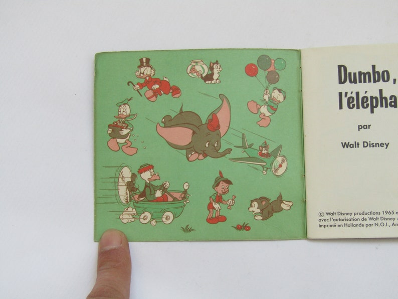 May include: Vintage children's book featuring Dumbo the elephant and other Disney characters. The cover shows illustrations of Dumbo flying, Donald Duck with balloons, and Pinocchio. Text reads "Dumbo, l'&eacute;l&eacute;phant" by Walt Disney.