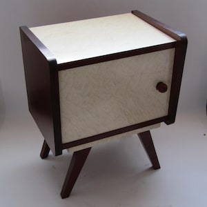 May include: A small, wooden nightstand with a single drawer and four legs. The drawer is made of a light-colored wood with a wood grain pattern. The nightstand is painted a dark brown color.