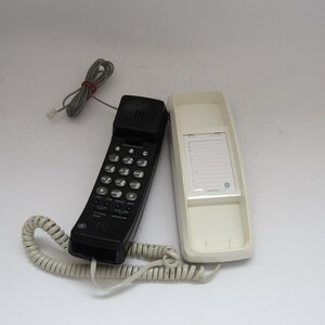 Puede incluir: Un teléfono con cable negro con teclado y un altavoz de pared blanco.