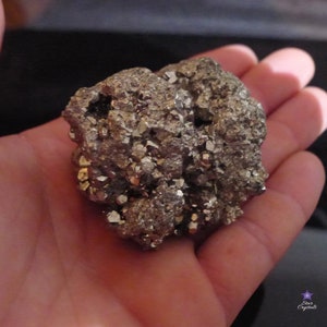 May include: A large, rough, metallic, gray, and gold, pyrite crystal cluster. The crystal is in the palm of a hand.