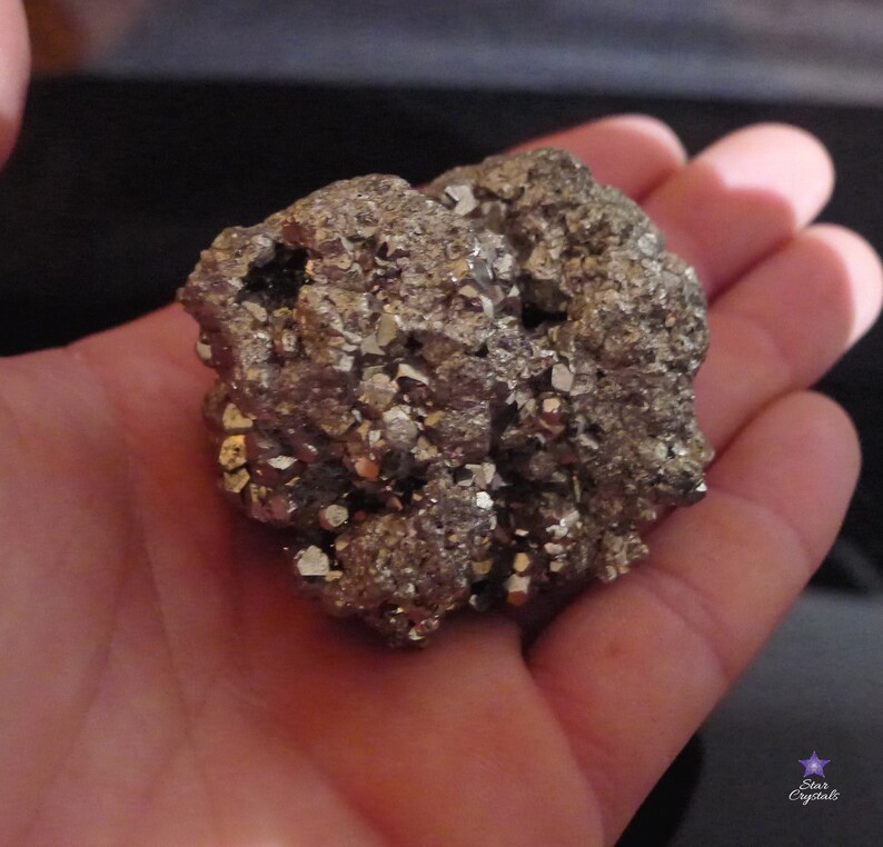 May include: A large, rough, metallic, gray, and gold, pyrite crystal cluster. The crystal is in the palm of a hand.