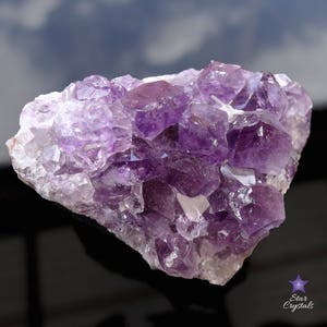 May include: A large amethyst cluster with many purple crystals. The crystals are clustered together in a natural formation. The amethyst is a deep purple color and has a shiny, translucent finish.