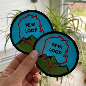 Pode incluir: Dois patches bordados azuis e verdes com o texto "PemI Loop" em letras pretas. O la&ccedil;o est&aacute; destacado em vermelho.