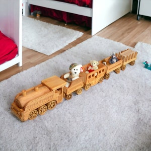 Puede incluir: Un tren de juguete de madera con la inscripción "Steam Express" en la parte delantera. El tren tiene varios vagones, cada uno con un animal de peluche. El tren es de madera de color marrón claro y está sobre una alfombra blanca.