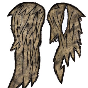 May include: A pair of brown fabric wings with a distressed look. The wings have a jagged edge and are outlined in black.