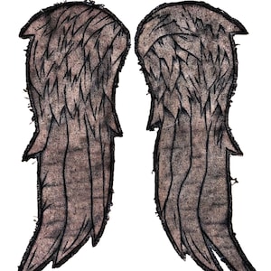 May include: Two brown fabric angel wings with black outlines and frayed edges. The wings are symmetrical, with detailed feather patterns. The background is plain white.