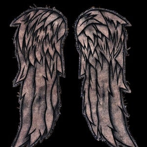 May include: A pair of gray fabric angel wings with black stitching and a distressed look. The wings are sewn together at the top and have a jagged edge.
