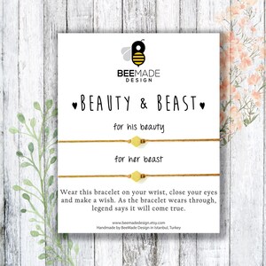 May include: A white card with a bee logo and the text "BEEMADE DESIGN" at the top. The text "BEAUTY & BEAST" is centered below the logo. Two brown string bracelets with gold beads are shown on the card. The text "for his beauty" is above the top bracelet and the text "for her beast" is above the bottom bracelet. The card also includes instructions on how to wear the bracelets and make a wish.