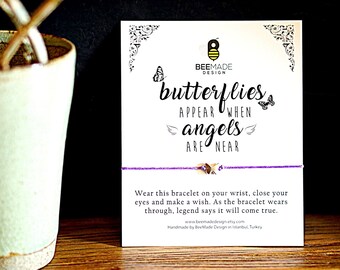 May include: Purple string bracelet with a silver butterfly charm. The card reads "butterflies appear when angels are near". Wear this bracelet on your wrist, close your eyes and make a wish. As the bracelet wears through, legend says it will come true.