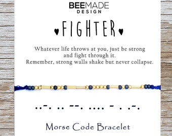 May include: A blue and gold beaded bracelet with a card that reads "FIGHTER" and "Morse Code Bracelet". The card also includes the text "Whatever life throws at you, just be strong and fight through it. Remember, strong walls shake but never collapse."