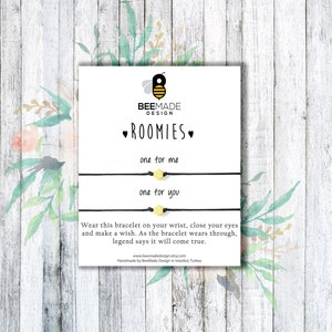 May include: A white card with black text that reads "BEEMADE DESIGN ROOMIES one for me one for you" and a small bee illustration. The card also includes the text "Wear this bracelet on your wrist, close your eyes and make a wish. As the bracelet wears through, legend says it will come true." and a website address.