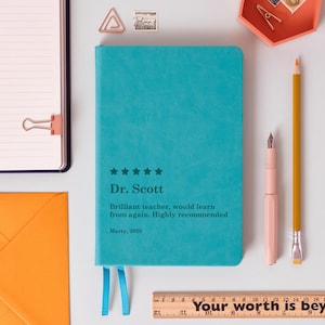 Könnte beinhalten: Ein türkisfarbenes Notizbuch mit dem Text "Dr. Scott" und einer Bewertung. Ein rosa Stift, ein gelber Bleistift und ein Holzlineal liegen neben dem Notizbuch. Auf dem Lineal steht "Your worth is bey".