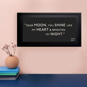May include: A black framed print with a white background and the text "DEAR MOON, YOU SHINE LIKE MY HEART & BRIGHTEN MY NIGHT."  The text is attributed to ROSA, AGE 7.