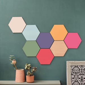 May include: A wall decorated with nine hexagonal tiles in various colours, including pink, light blue, purple, green, red, orange, and wood. The tiles are arranged in a honeycomb pattern.