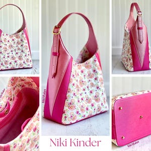 May include: A pink and floral patterned shoulder bag with a single handle. The bag features a combination of pink leather and a floral fabric with a teddy bear pattern. The bag has a gold buckle and the text "Niki Kinder".