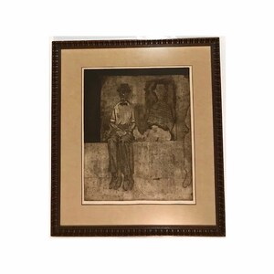 May include: A framed black and white etching of a man sitting on a ledge. The man is wearing a hat and a button-down shirt. The etching is in a brown frame.