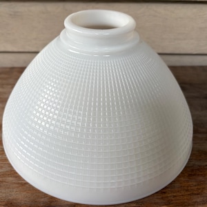 Könnte beinhalten: Ein weißer Lampenschirm aus Milchglas in Kuppelform mit einem erhabenen Gittermuster auf der Außenfläche. Der Schirm verfügt über eine glatte, kreisförmige Öffnung an der Oberseite mit einem dicken, abgerundeten Rand zur Befestigung.