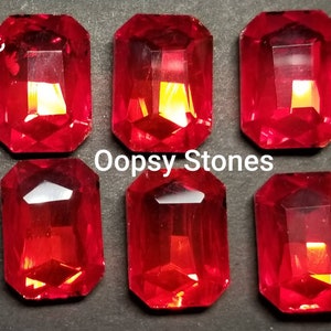 May include: Six red, rectangular, faceted glass gems, labeled "Oopsy Stones" and "6pc".