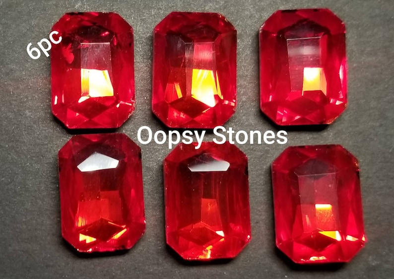 May include: Six red, rectangular, faceted glass gems, labeled "Oopsy Stones" and "6pc".