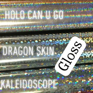 Op de afbeelding: Close-up van verschillende rollen decoratief vinyl met diverse afwerkingen. De rollen bevatten "Orange U Holo", "Holo Can U Go", "Dragon Skin", "Kaleidoscope" en "Red Shimmer". De afbeelding bevat ook de woorden "Gloss" en "Matte".