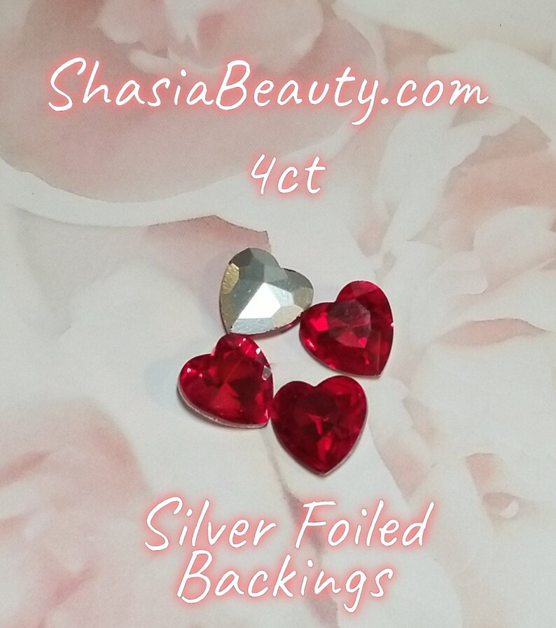 May include: Four red heart-shaped rhinestones with silver foiled backings. The rhinestones are on a white background with the text "ShasiaBeauty.com 4ct Silver Foiled Backings".