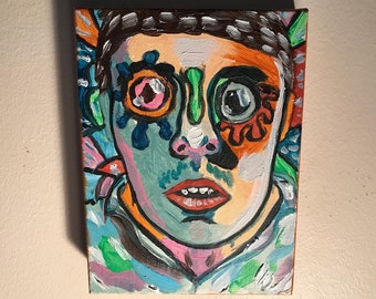 May include: A colorful abstract painting of a face with bright green, blue, orange, pink, and white paint. The face has a large, round eye with a pink iris and a smaller, round eye with a black iris. The mouth is open and red.