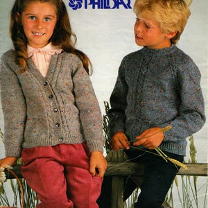 May include: Vintage knitting pattern cover showing two children. The girl wears a grey cardigan and red corduroy trousers. The boy wears a grey sweater and black corduroy trousers. The pattern is for double knitting, sizes 56-81 cm.