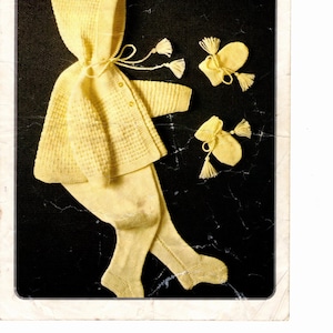 May include: A vintage baby outfit in pale yellow, including a hooded jacket, leggings, and mittens. The jacket has button closures and a tie. The image also includes the text "Copley Baby 4 ply" and measurements of 19-21 inches (48-53 cm).