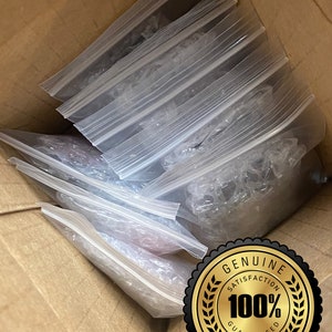 May include: A cardboard box containing multiple clear plastic zip-lock bags. The bags hold various items, some protected by bubble wrap. A gold seal with the text "GENUINE SATISFACTION 100% GUARANTEED PRODUCT" is visible.