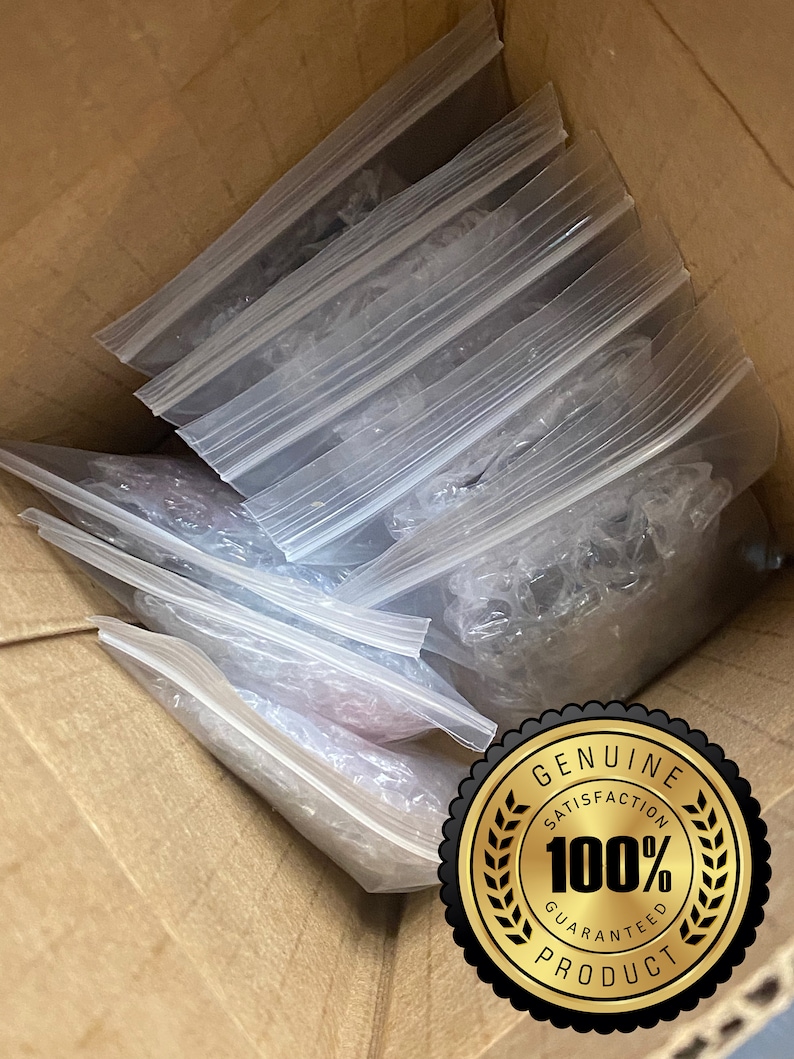 May include: A cardboard box containing multiple clear plastic zip-lock bags. The bags hold various items, some protected by bubble wrap. A gold seal with the text "GENUINE SATISFACTION 100% GUARANTEED PRODUCT" is visible.